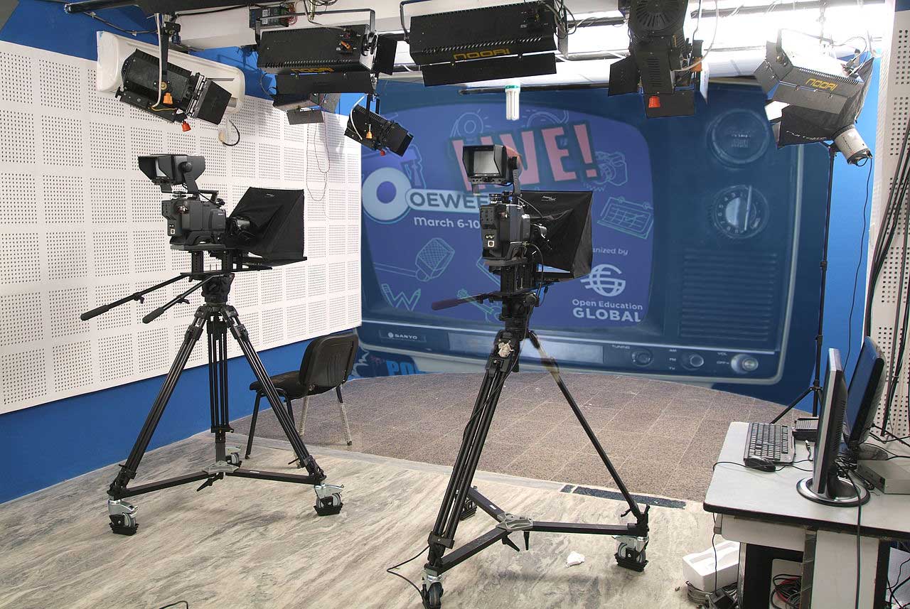 TV studio with t large cameras pointed at blue screen which displays the OEWeek Live logo