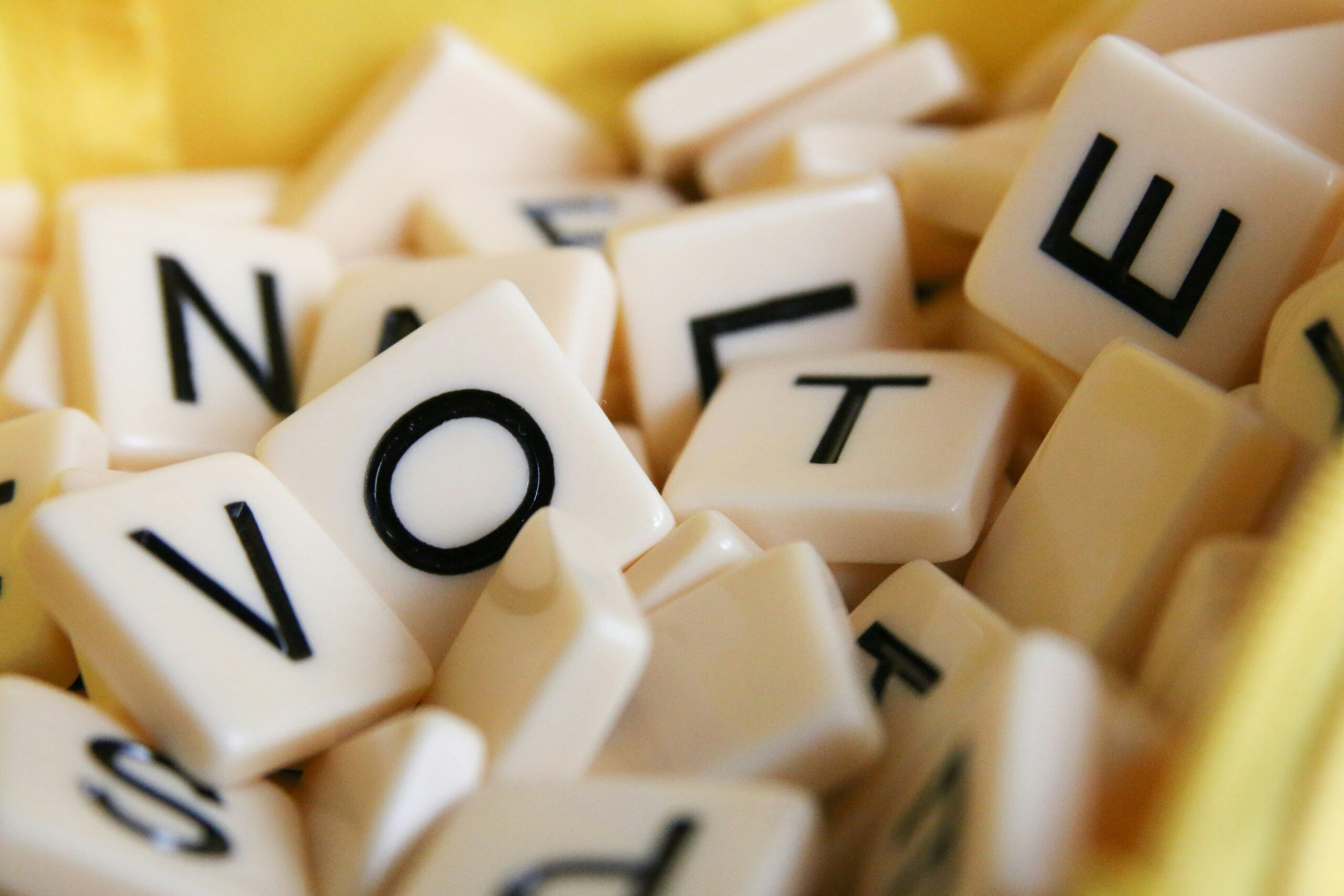 A pile of scrabble pieces against a yellow backgroup spelling out "vote" - Photo by Glen Carrie from Unsplash